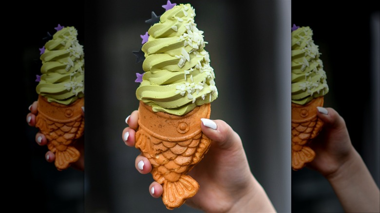 Hand holding carp bread with ice cream stuffed in the mouth