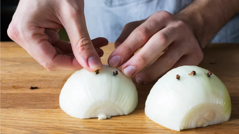 Cloves being pressed into onion