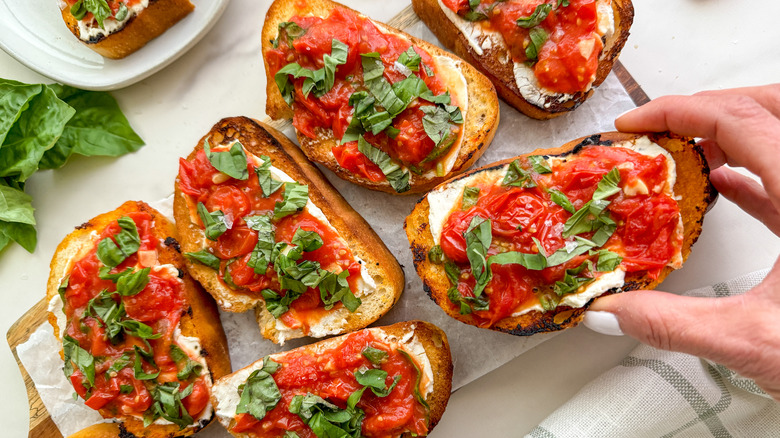 hand holding piece of bruschetta