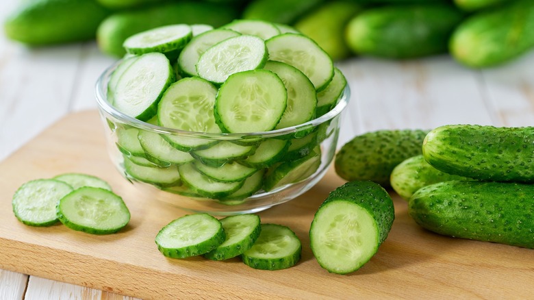 A bowl of sliced cucumbers on a board