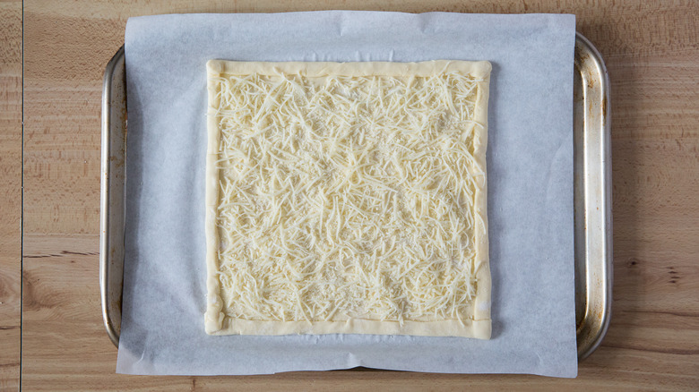 cheese covered puff pastry on baking sheet