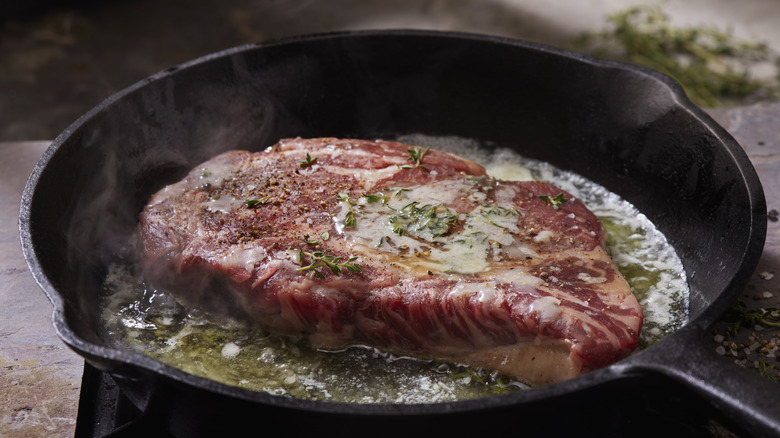 steak cooking in a cast iron pan