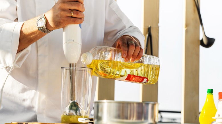 Chef pouring olive oil into blender