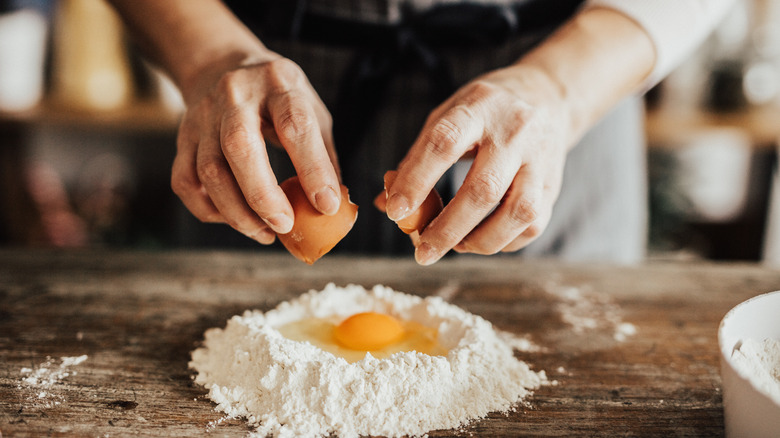 Person adding egg to flour