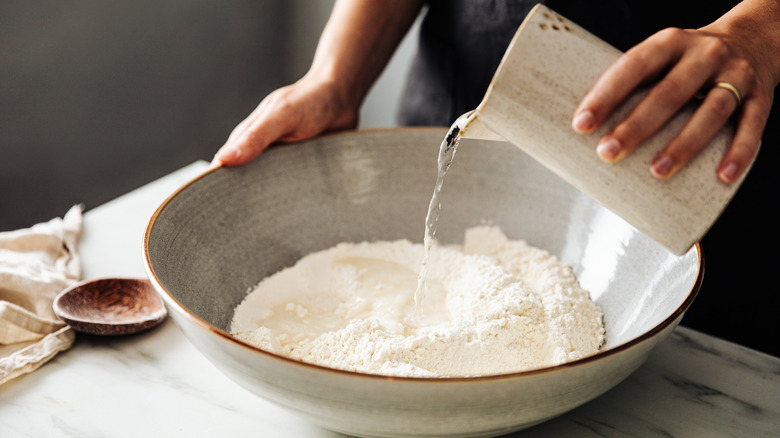 Person pouring water into flour