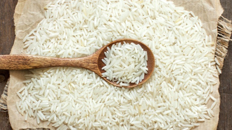 Dry basmatic rice on paper with a wooden spoon