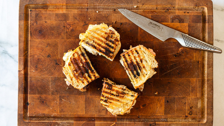 Knife with two cut grilled panini sandwiches on board