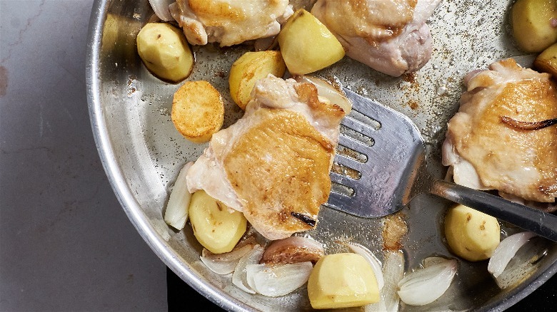 spatula lifting browned chicken in skillet