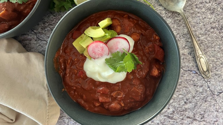 bowl of chili with toppings next to metal spoon