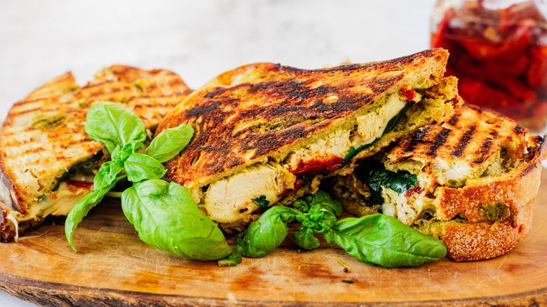 three chicken panini sandwiches on a cutting board