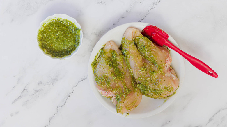 uncooked chicken breasts coated with pesto on plate