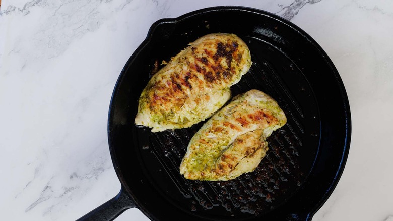 Grilled pesto chicken breasts in cast iron pan