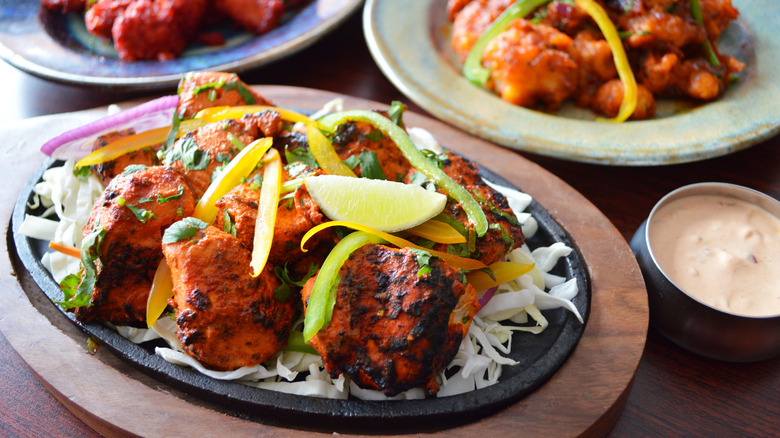 plate of chicken tandoori and other spicy dishes in the background