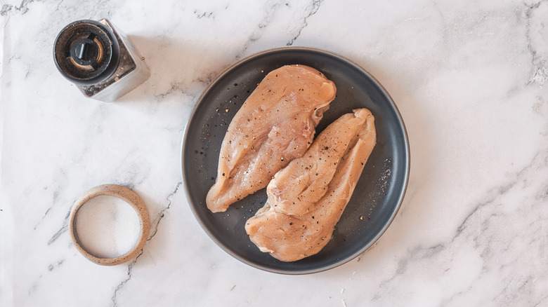 Chicken breasts in plate with salt and pepper