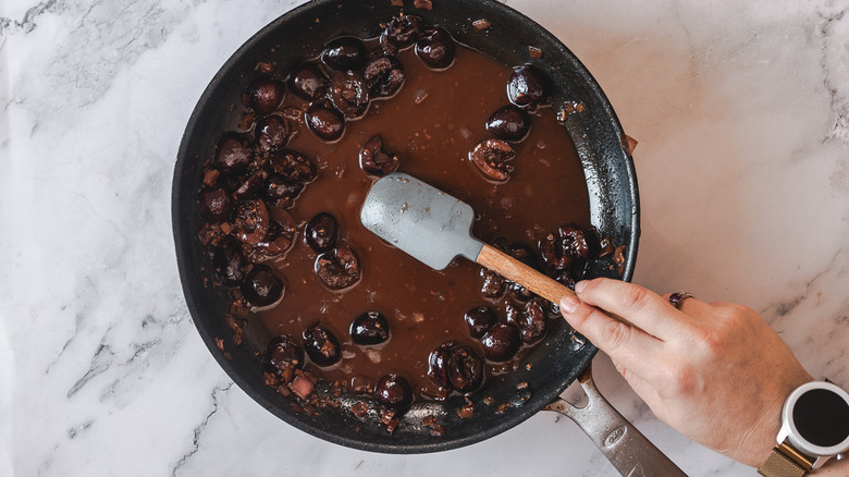 Hand stirring cherry sauce with spatula