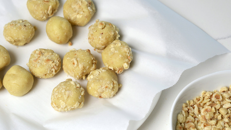 Hazelnut thumbprint cookie dough rolled in crushed hazelnuts