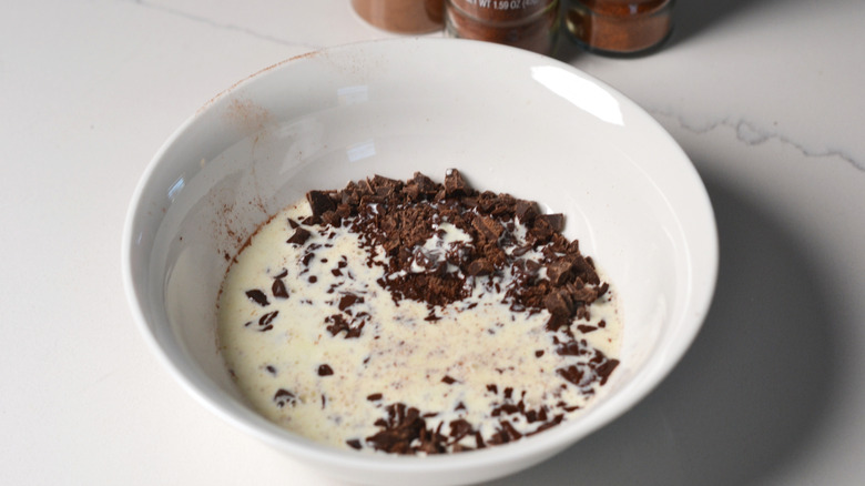 Chopped chocolate combined with hot heavy cream in a bowl