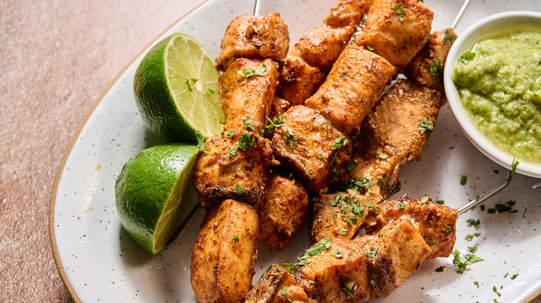 salmon skewers on a plate with limes