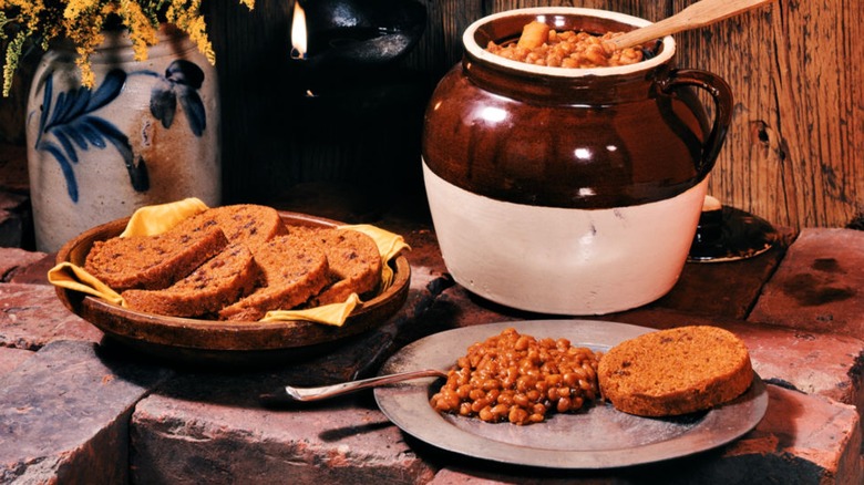 Baked bean crock and bread next to a served plate