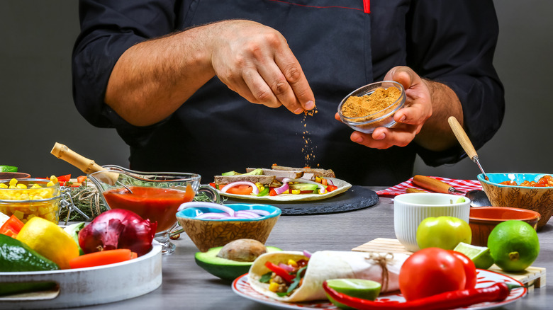 chef pouring spice on fajita