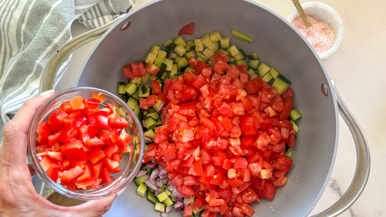 hand adding tomatoes to pot