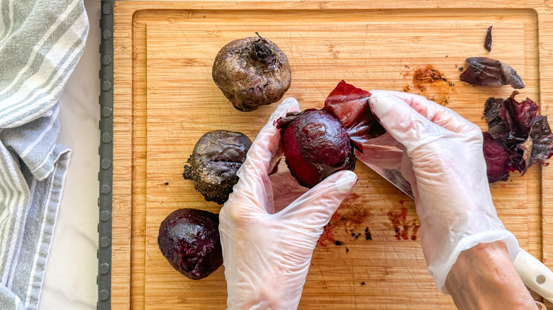 gloved hands peeling beets