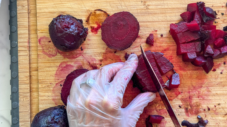 gloved hands dicing beets