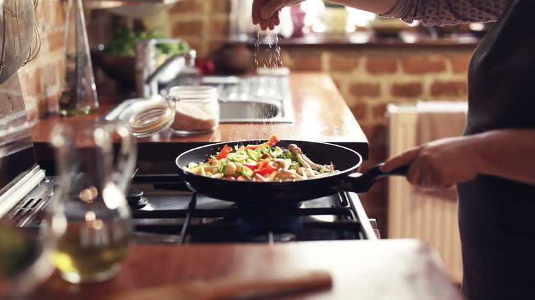 adding spices to a pan of food