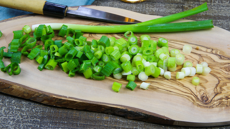 Chopped scallions on cutting board with oil bottles