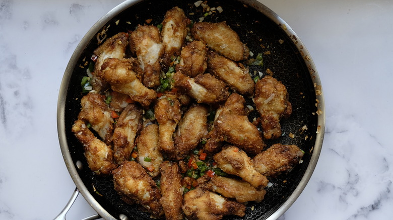 frying pan with chicken wings and veggies