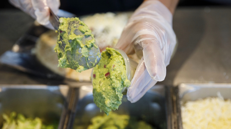 Chipotle worker scooping guacamole