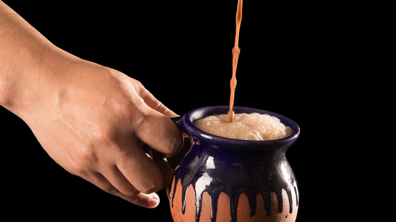 hand pouring chocolate-atole into mug