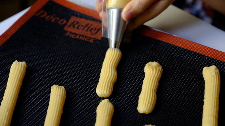 Hand uses piping bag to make eclairs 