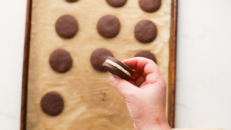 Hand holding filled chocolate sandwich cookie