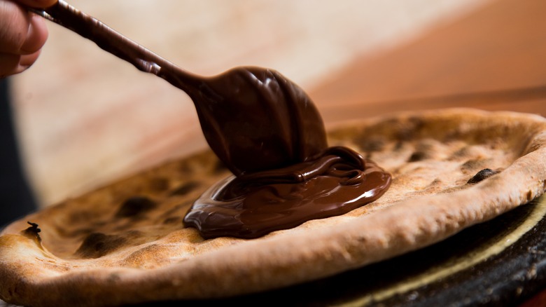 Spoon ladling chocolate onto crust