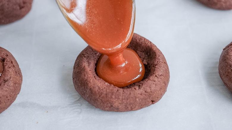 spoon drizzling caramel into cookie