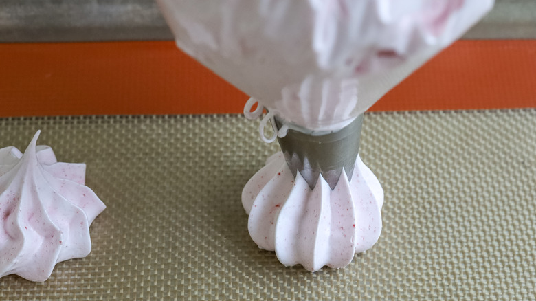 meringue batter being piped onto a baking sheet