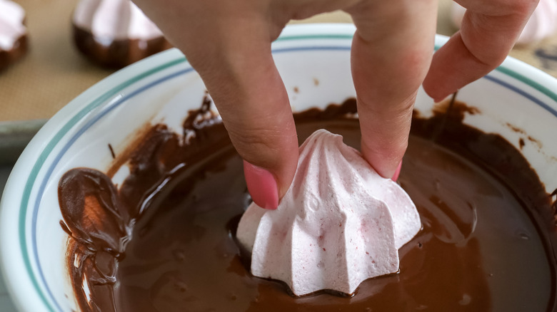 chocolate strawberry meringue cookies being dipped in chocolate