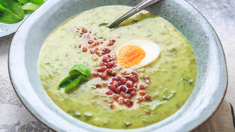 bowl of green soup with bacon topping