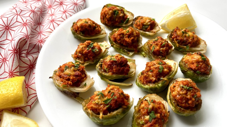 chorizo-stuffed Brussels sprout on a plate with lemon wedges