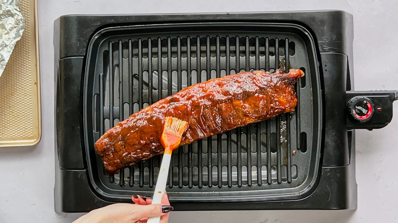 brushing barbecue sauce on ribs