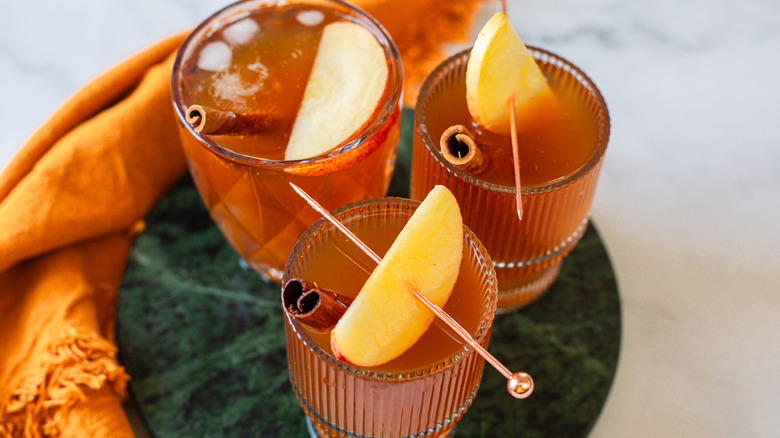 Three kombucha glasses with garnish on green tray