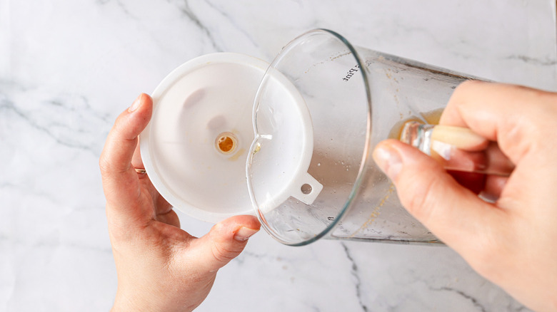 Pouring kombucha through funnel into bottle