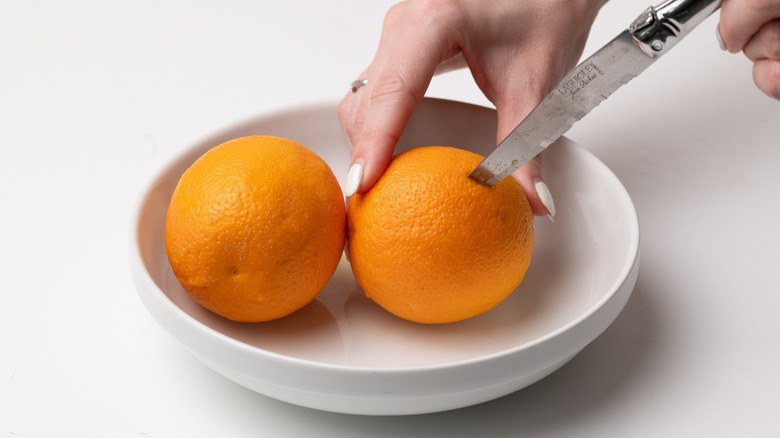 piercing oranges with a knife