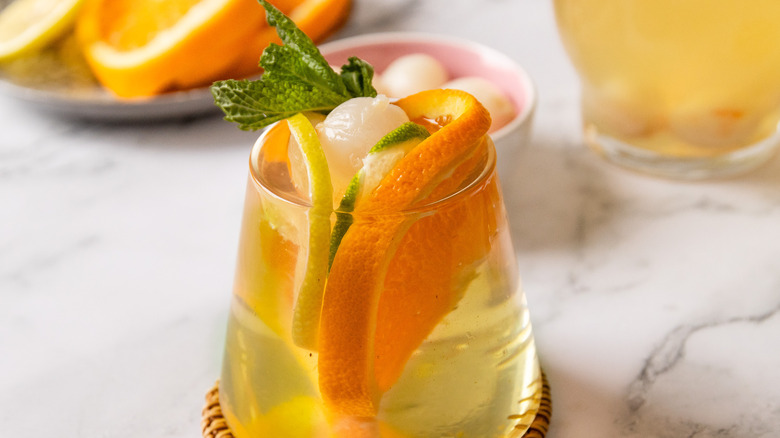 One glass of sangria with pitcher and citrus in background