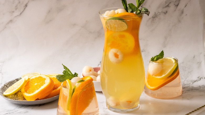 Two glasses of sangria with pitcher and citrus in background