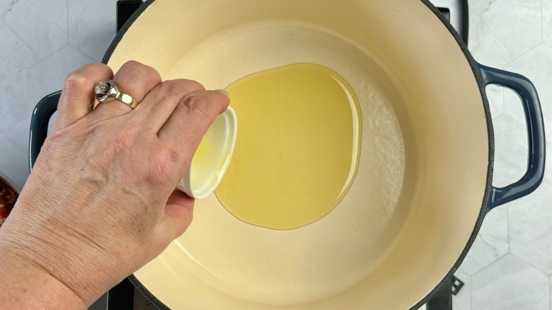 hand pouring oil in pot