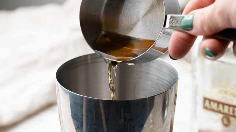 pouring amaretto into cocktail shaker 