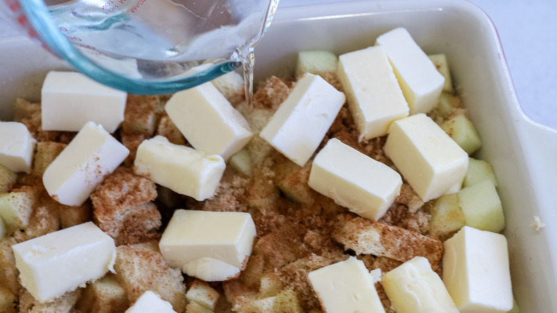 Water being drizzled over an apple brown betty mixture