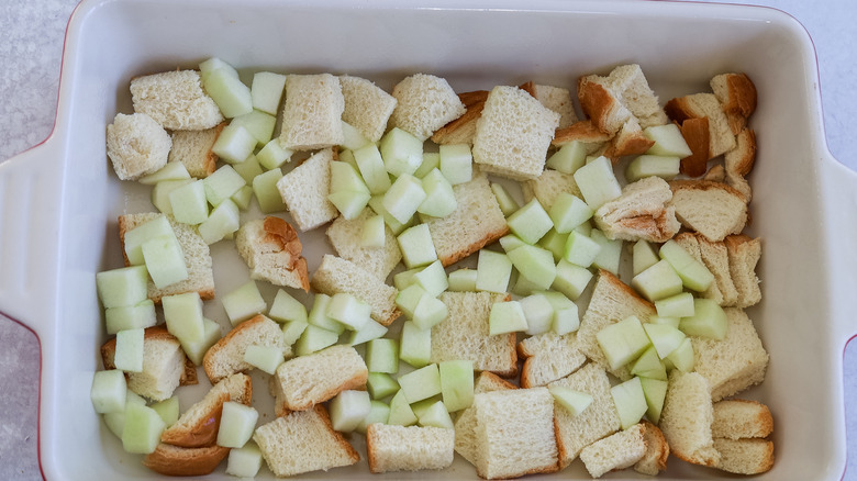 Diced apples and bread cubes in the bottom of a baking pan